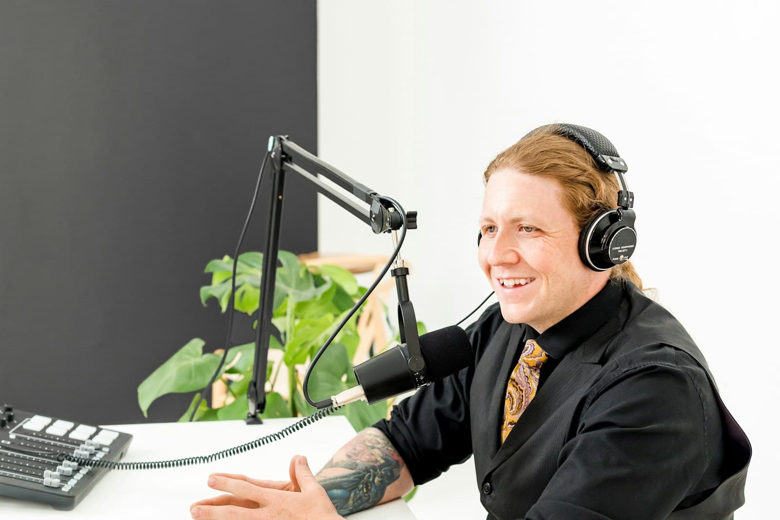 A professional speaking into a studio microphone while wearing headphones