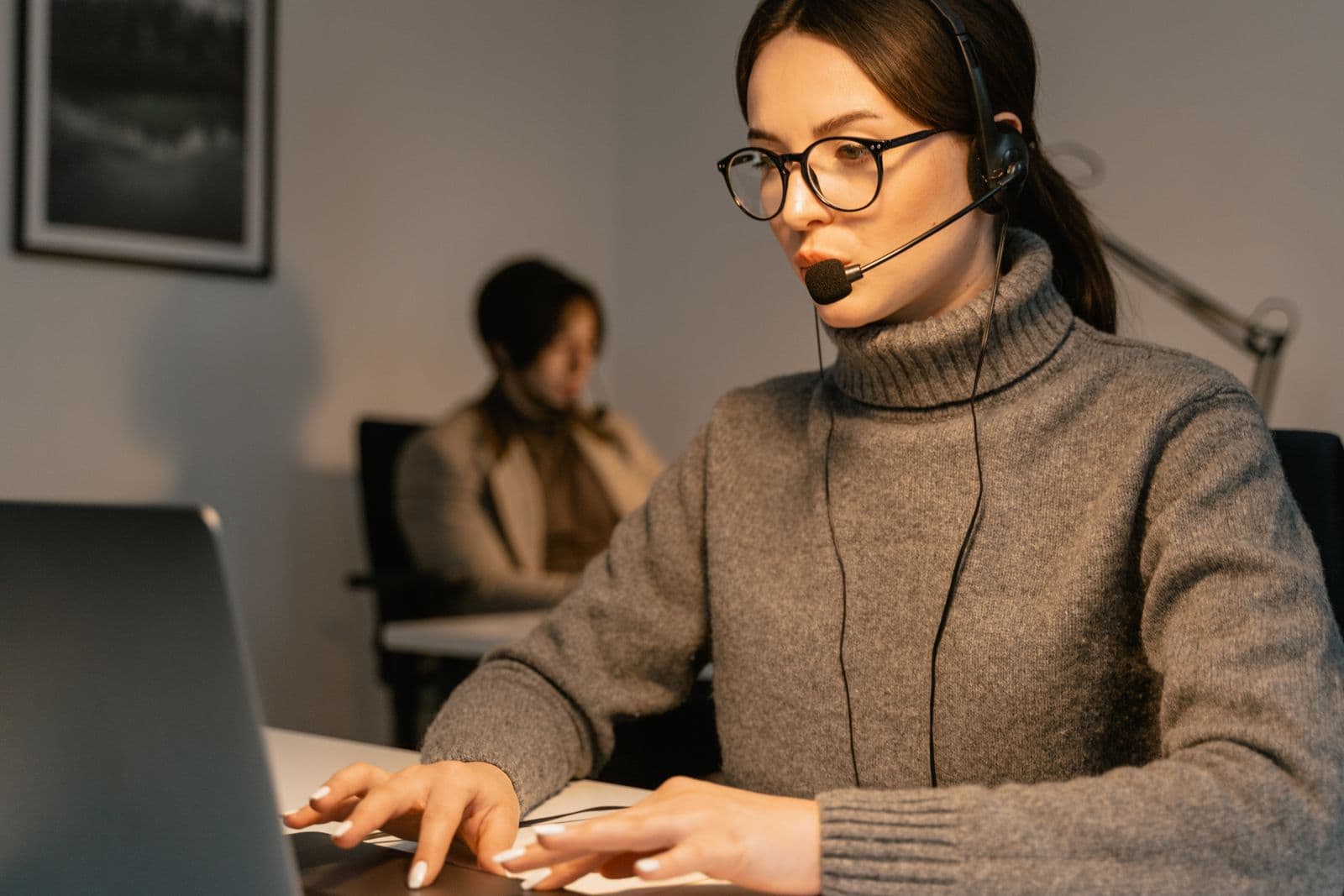 A focused customer support specialist listening through a headset